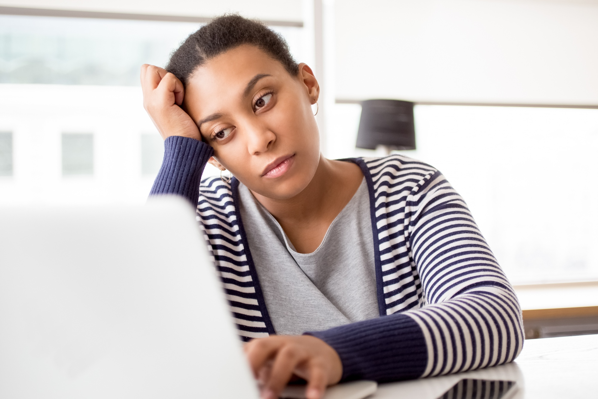 A lady looking at her laptop worried about her not closing clients.